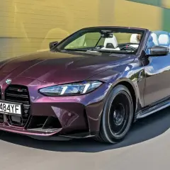 M4 CS kabriolet w kolorze śliwkowym sunie po drodze.