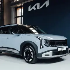 Nowy Kia Seltos prezentuje się nowocześnie na tle granatowej ściany z logo marki.