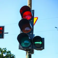 Sygnalizator S2 z zieloną strzałką w prawo i czerwonym światłem na głównym słupku. Niebo błękitne.