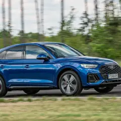 Błękitny Audi Q5 Sportback 2025 w ruchu, z rozmytym tłem lasu. Dynamiczna sylwetka i sportowy charakter.