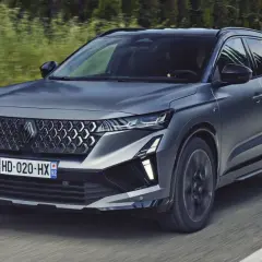 Nowy Austral Renault pędzi po drodze, otoczony zielenią.