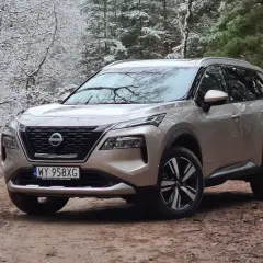 Złoty Nissan X-Trail na leśnej drodze zimą. Wiele osób szuka nissan x trail opinie, ten SUV świetnie radzi sobie w trudnych warunkach.