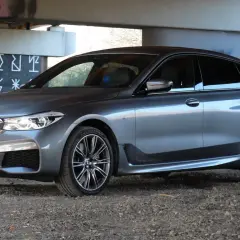 Eleganckie bmw 640d w szarym kolorze zaparkowane pod mostem z graffiti.
