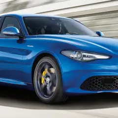 Błękitne Alfa Romeo Giulia Q4 Veloce w ruchu, z żółtymi zaciskami hamulcowymi i sportowymi felgami.