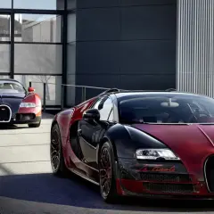 Dwa Bugatti Veyron w kolorach czarnym i czerwonym przed nowoczesnym budynkiem.