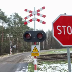 Przejazd kolejowy bez zapór z czerwonym światłem i znakiem STOP. Uważaj na tory!