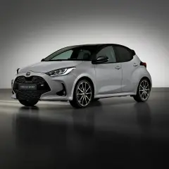 Srebrny Toyota Yaris GR Sport z czarnym dachem i sportowymi felgami stoi na ciemnej podłodze.