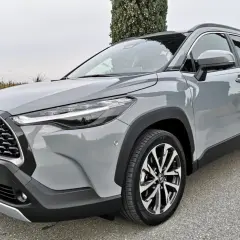 Szary Toyota Corolla SUV stoi na drodze, otoczony zielenią.