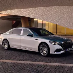 Elegancki Maybach S580 w dwukolorowym malowaniu, zaparkowany przed nowoczesnym budynkiem o geometrycznej fasadzie.