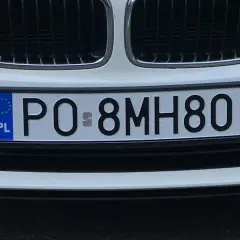 Białe auto z tablicą rejestracyjną PO 8MH80.