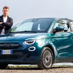 Młody mężczyzna stoi obok swojego nowego, turkusowego fiat mini 500 nad jeziorem.