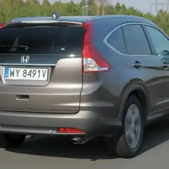 Honda CR-V 2.0 benzyna w kolorze brązowym jedzie po drodze.