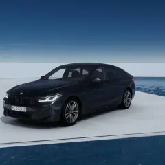 Eleganckie bmw g32 w ciemnym kolorze prezentuje się na platformie nad wodą, z błękitnym niebem w tle.