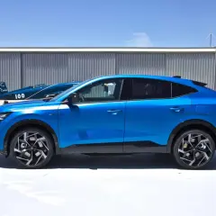 Niebieski Renault Rafale prezentuje swoje dynamiczne linie i imponujące wymiary na tle hangarów lotniczych.