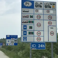Znak D43 informuje o opłatach drogowych i ograniczeniach prędkości. Na drodze obowiązują różne limity dla samochodów i ciężarówek.