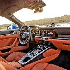 Wnętrze Porsche 911 GTS w kolorze pomarańczowym, z nowoczesnym kokpitem i ekranem multimedialnym.