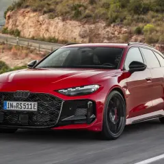 Czerwone, nowe RS5 Avant sunie po krętej drodze w górach.
