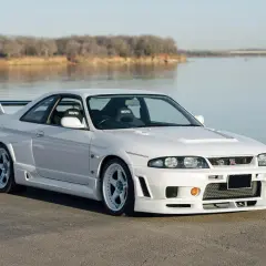 Białe r33 GT-R z siedzeniami Nismo stoi nad jeziorem.