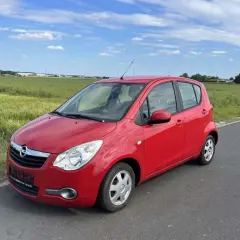 Czerwony Opel Agila 1.2 na tle zielonych pól i błękitnego nieba.