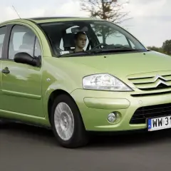 Zielony Citroen C3 z 2003 roku jedzie po drodze. Za kierownicą siedzi młody mężczyzna.