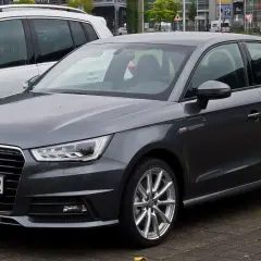 Ciemnoszary Audi 1 z niemieckimi tablicami rejestracyjnymi D.GS 8802 stoi obok białego SUV-a.