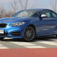 Niebieskie BMW 235i na pasach. Sportowy samochód z charakterystycznym grillem i felgami.