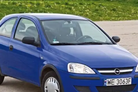 Niebieski Opel Corsa C 1.2 z tablicą WE 3063F stoi na tle zielonej łąki.