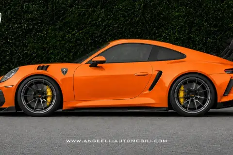 Pomarańczowy Porsche RWB z czarnym spoilerem i felgami, na tle zielonego żywopłotu.