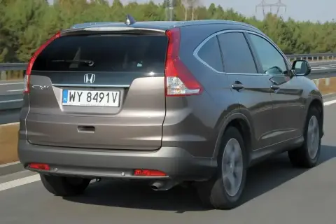 Honda CR-V 2.0 benzyna w kolorze brązowym jedzie po drodze.