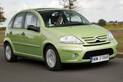 Zielony Citroen C3 z 2003 roku jedzie po drodze. Za kierownicą siedzi młody mężczyzna.