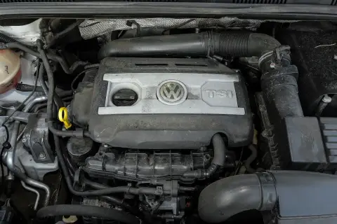 Silnik 2.0 TSI Volkswagena, widok z góry. Widać pokrywę silnika z logo VW i napisem TSI, elementy układu dolotowego i chłodzenia.