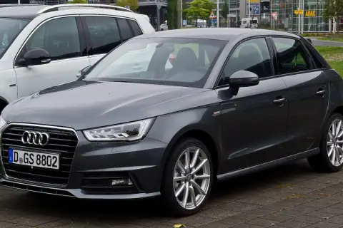 Ciemnoszary Audi 1 z niemieckimi tablicami rejestracyjnymi D.GS 8802 stoi obok białego SUV-a.