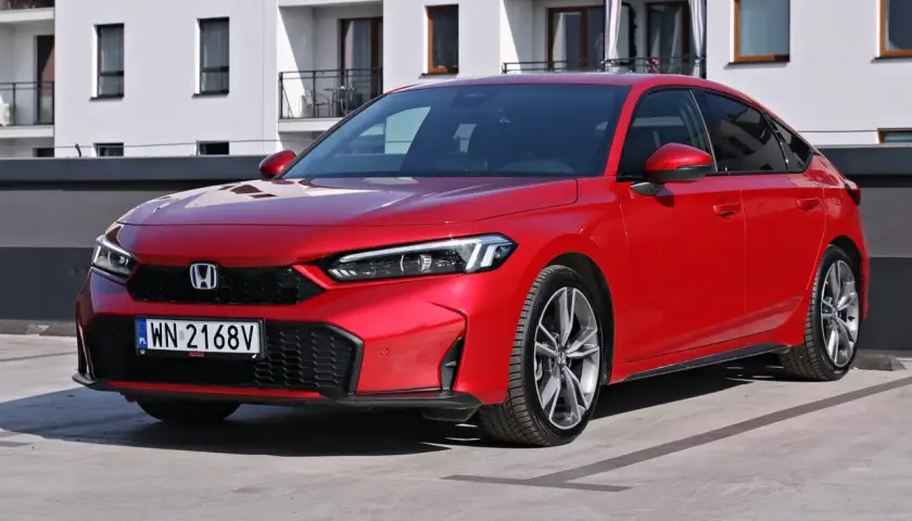 Czerwony Honda Civic Si na parkingu przed nowoczesnym budynkiem. Sportowy wygląd i dynamiczna linia nadwozia.