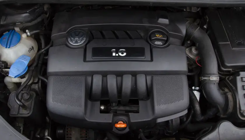 Silnik Volkswagena z oznaczeniem 1.6 MPI. Widoczny jest czarny plastikowy kolektor, logo VW i zbiornik płynu chłodniczego.