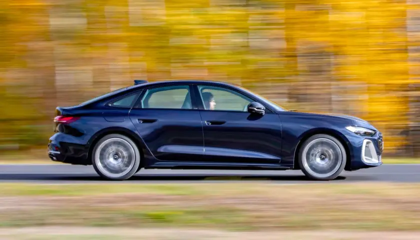 Ciemnoniebieskie Audi A4 B10 w ruchu, z rozmytym jesiennym tłem.