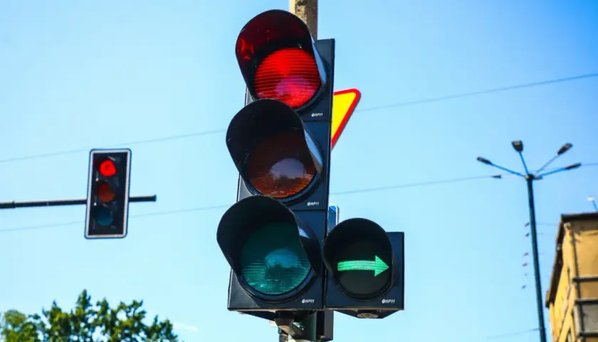 Sygnalizator S2 z zieloną strzałką w prawo i czerwonym światłem na głównym słupku. Niebo błękitne.