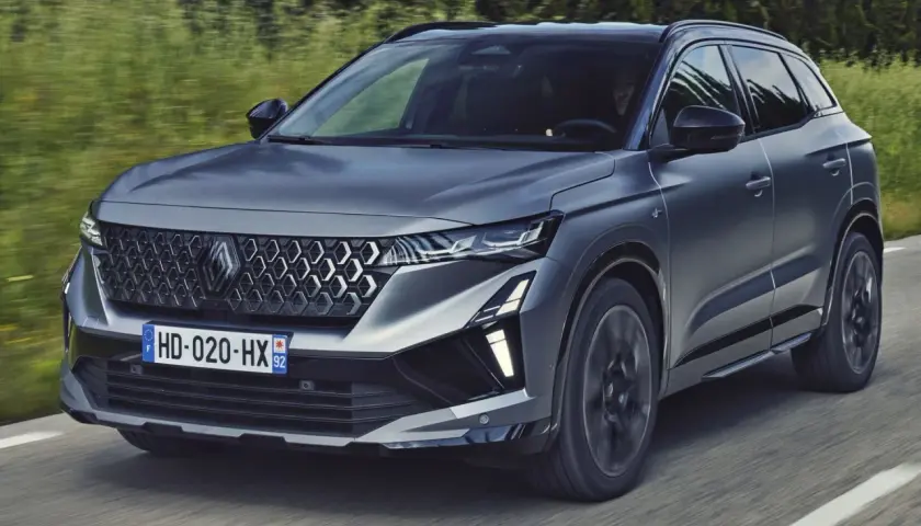 Nowy Austral Renault pędzi po drodze, otoczony zielenią.