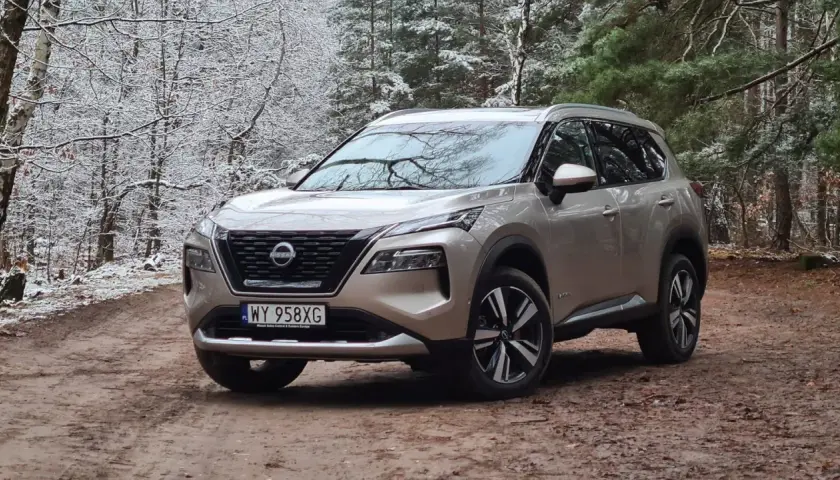 Złoty Nissan X-Trail na leśnej drodze zimą. Wiele osób szuka nissan x trail opinie, ten SUV świetnie radzi sobie w trudnych warunkach.