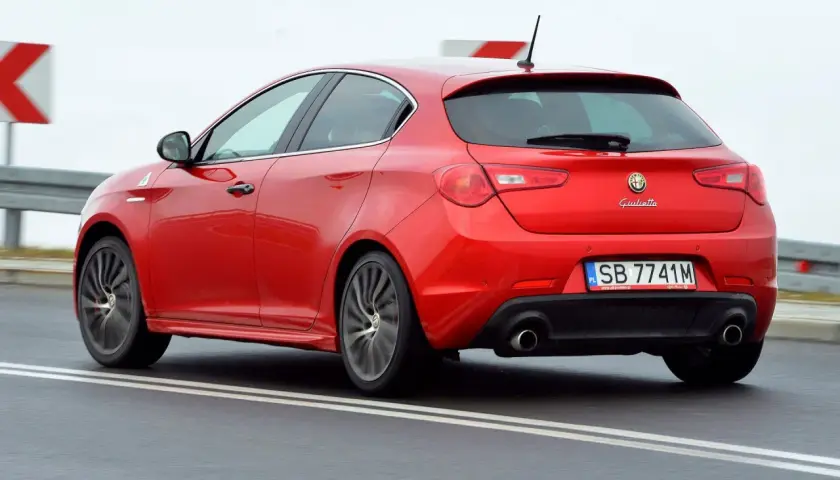 Czerwona Alfa Romeo Giulietta w ruchu. Wiele osób szuka alfa romeo giulietta opinie, by poznać wrażenia z jazdy tym modelem.