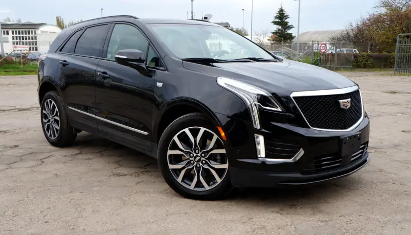 Czarny Cadillac XT5 z chromowanymi detalami i charakterystyczną atrapą chłodnicy stoi na betonowym placu.
