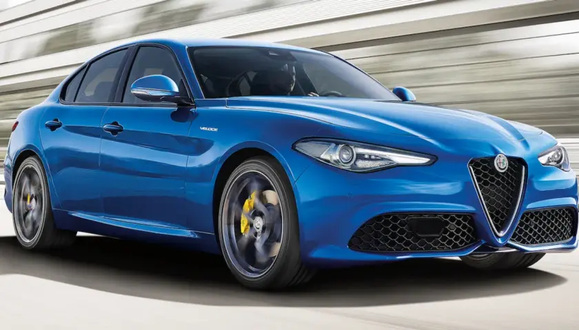 Błękitne Alfa Romeo Giulia Q4 Veloce w ruchu, z żółtymi zaciskami hamulcowymi i sportowymi felgami.