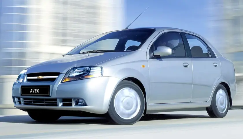 Srebrny Chevrolet Kalos, model Aveo, pędzi po drodze, rozmywając tło.