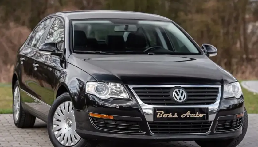 Czarny Volkswagen Passat B6 na tle drzew. Elegancki, lśniący lakier i chromowane detale podkreślają jego klasę.