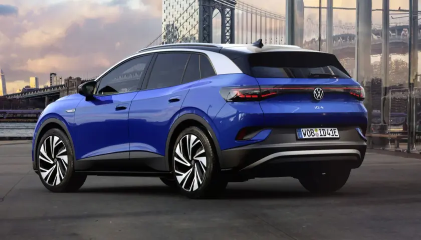 Niebieski Volkswagen ID.4 z białym dachem, zaparkowany na tle miasta z mostem i nowoczesnymi budynkami.