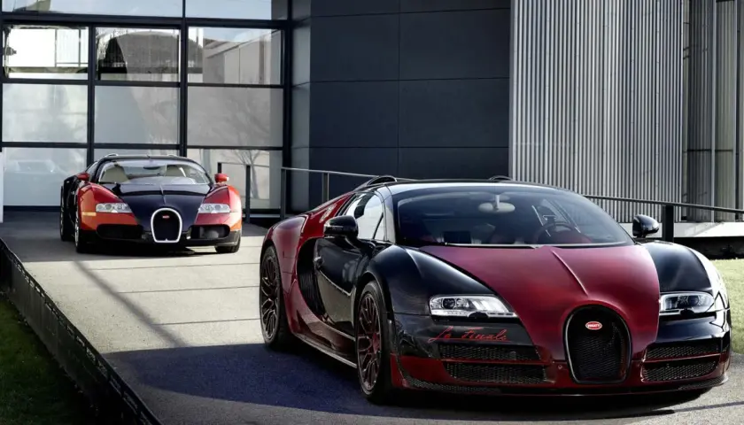 Dwa Bugatti Veyron w kolorach czarnym i czerwonym przed nowoczesnym budynkiem.