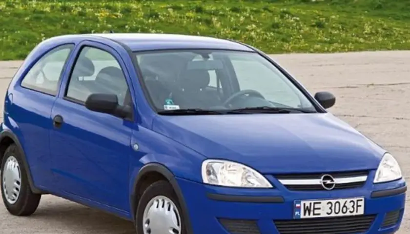 Niebieski Opel Corsa C 1.2 z tablicą WE 3063F stoi na tle zielonej łąki.