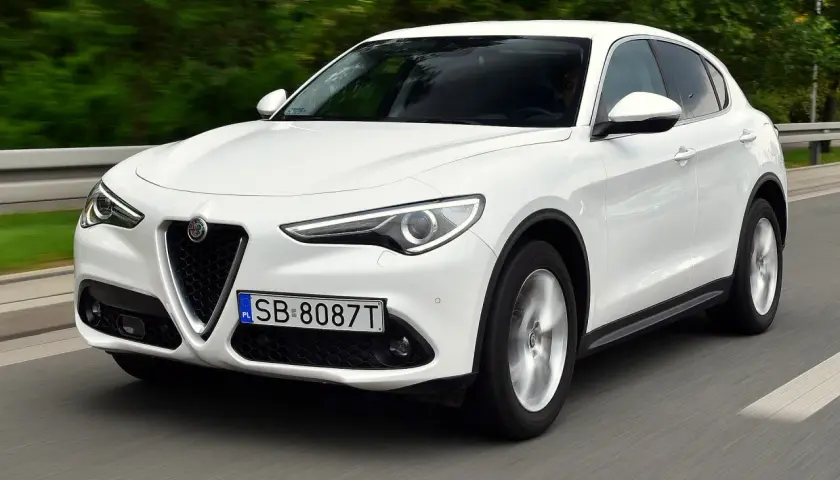 Białe Alfa Romeo Stelvio w ruchu. Kierowcy chwalą jego dynamikę, co potwierdzają liczne alfa romeo stelvio opinie.