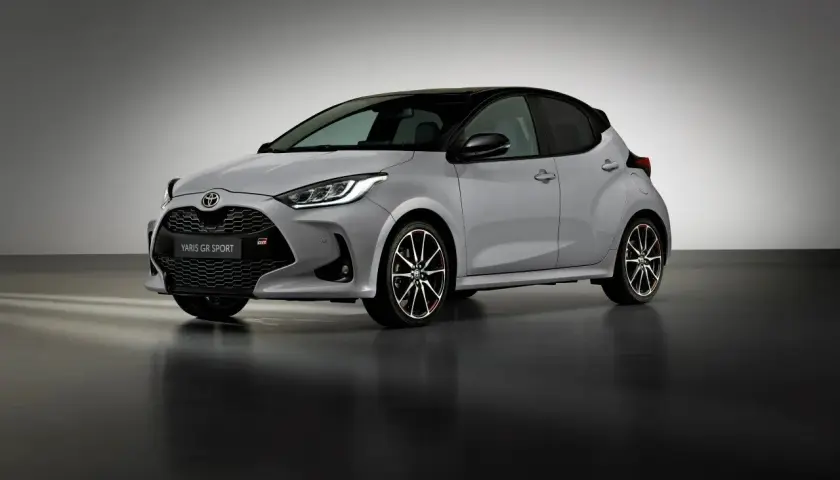 Srebrny Toyota Yaris GR Sport z czarnym dachem i sportowymi felgami stoi na ciemnej podłodze.