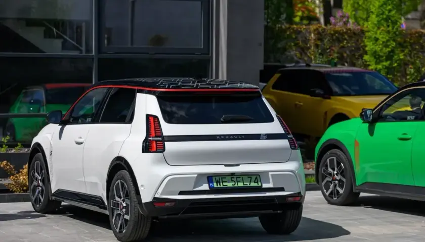 Nowy Renault 5 w białym kolorze, obok zielonego i żółtego, prezentuje się nowocześnie.