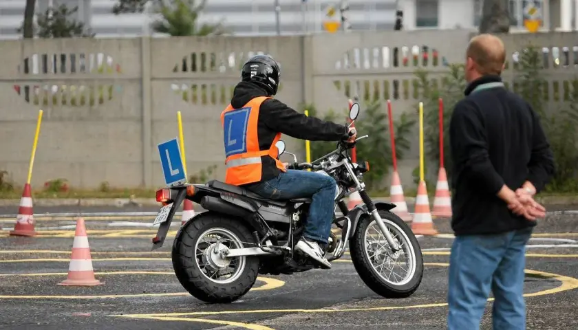 Nauka jazdy na motorowerze na placu manewrowym. Czy to szansa na prawo jazdy AM za darmo? Instruktor obserwuje kursanta.